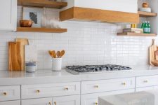 a welcoming white kitchen with shaker cabinets, stone countertops, a white skinny tile backsplash and light-stained wooden touches