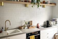 a white Scandinavian kitchen with an off-white skinny tile backsplash, stone countertops and an open shelf with dishes and decor