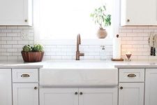 a white modern farmhouse kitchen with white skinny tiles and black grout on the backsplash and copper touches here and there