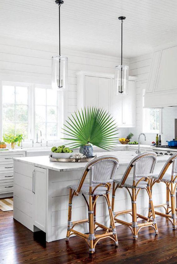 a white tropical kitchen with tropical plants, rattan chairs with blue upholstery and with a contemporary feel