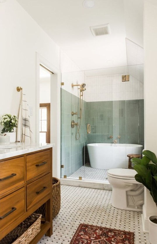 An elegant mid century modern bathroom with skinny green tiles, a shower and a tub, a mosaic tile floor, a stained vanity and a rug