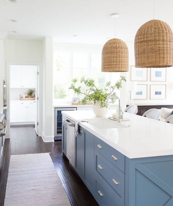 elegant pblue cabinets with a pure white countertop and wicker lamps over them make up a chic look