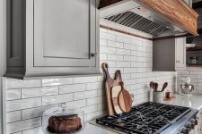 glossy off-white tiles on the backsplash are highlighted with black grout and perfectly match the grey cabinets
