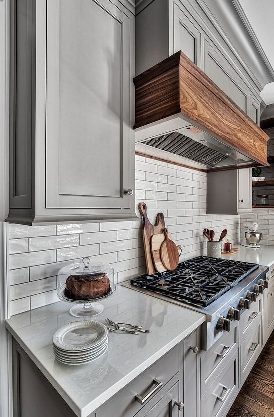 Glossy off white tiles on the backsplash are highlighted with black grout and perfectly match the grey cabinets