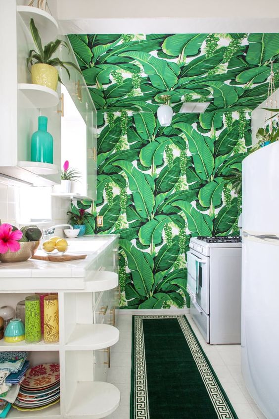 sleek wite cabinets with a banana leaf print taking over the whole space and an emerald rug