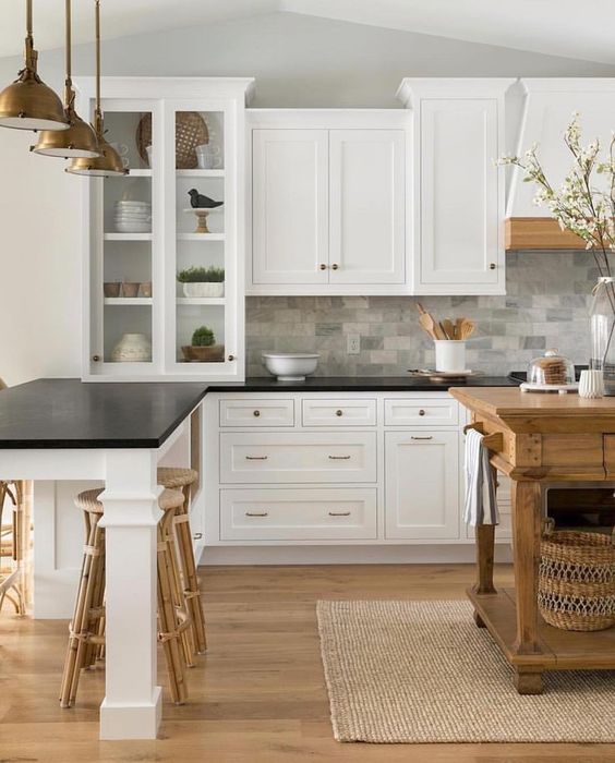 vintage-inspired white cabinets with black countertops and a grey marble tile backsplash for a cozy farmhouse kitchen