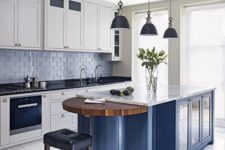 white cabinets with black countertops, a blue kitchen island with a white countertop and a wooden part seem very contrasting