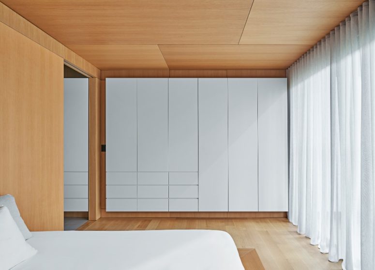The master bedroom is super minimal and sleek - there's a bed and a large storage unit plus lots of light colored wood