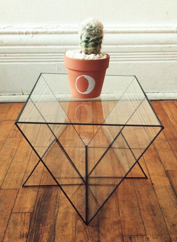 a glass geometric shaped table with black framing is a cool way to make a statement with its shape