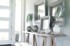 06 a neutral tropical entryway with light-colored wooden furniture, vases with tropical leaves, driftwood and mirrors in metal frames