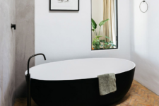 07 The bathroom is done with a black and white bathtub a black faucet and a large mirror