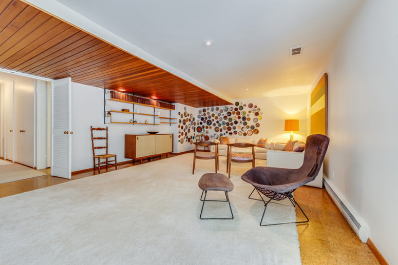 The third living area is done with lots of elegant mid-century modern furniture and a wall with decorative plates