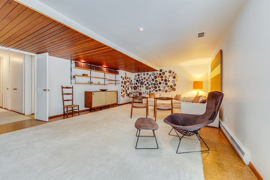 The third living area is done with lots of elegant mid century modern furniture and a wall with decorative plates