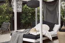 07 a cabana-style wooden daybed with a hanging blakc lamp, a curtain and lot sof pillows and blankets welcomes with its look