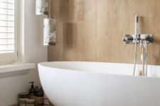 08 The bathroom is done with light colored wood and a modern oval tub