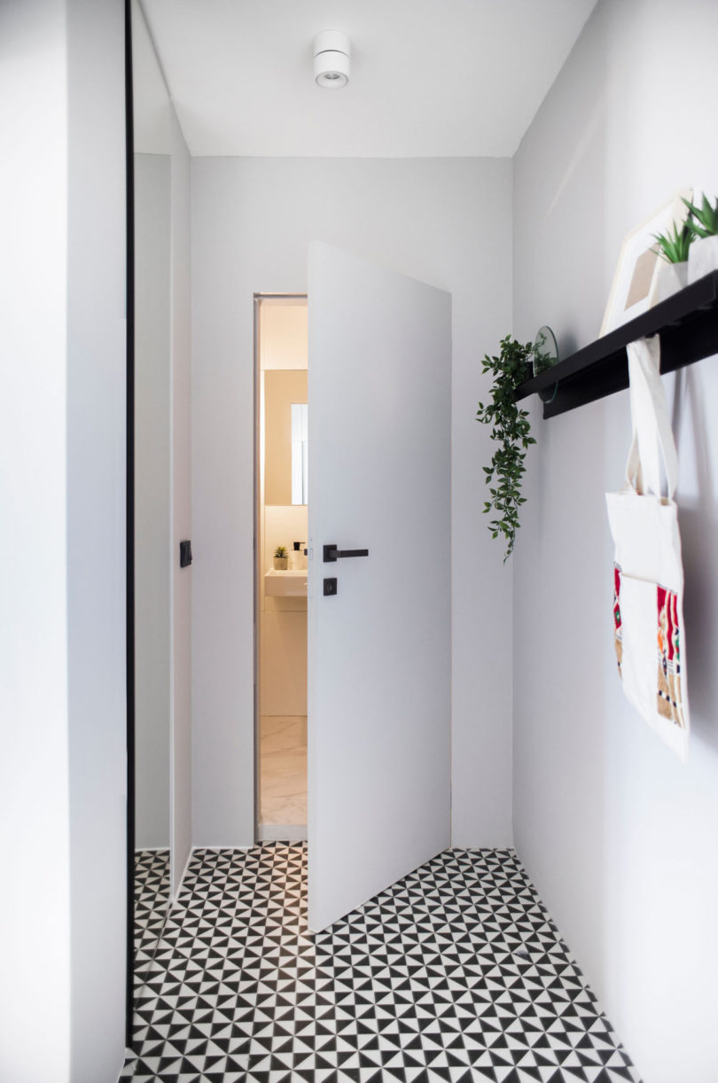 The entryway is sleek and simple, with a patterned floor and a large mirror