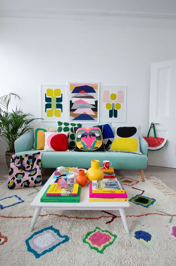 A bright living room with colorful pillows, artworks, a rug and books   all the colors are brought with accessories