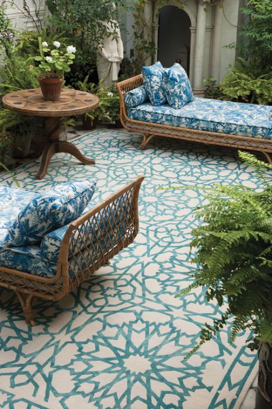 a couple of elegant rattan daybeds dressed up with blue and white printed bedding that matches the mosaic floor