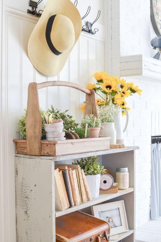 a farmhouse cabinet instead of a console, a tool box with platers and a floral arrangement in a vintage pitcher