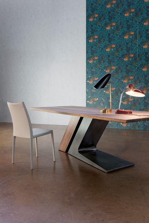 a large sculptural desk in rich stain and dark metal features a large comfortable base that makes a statement