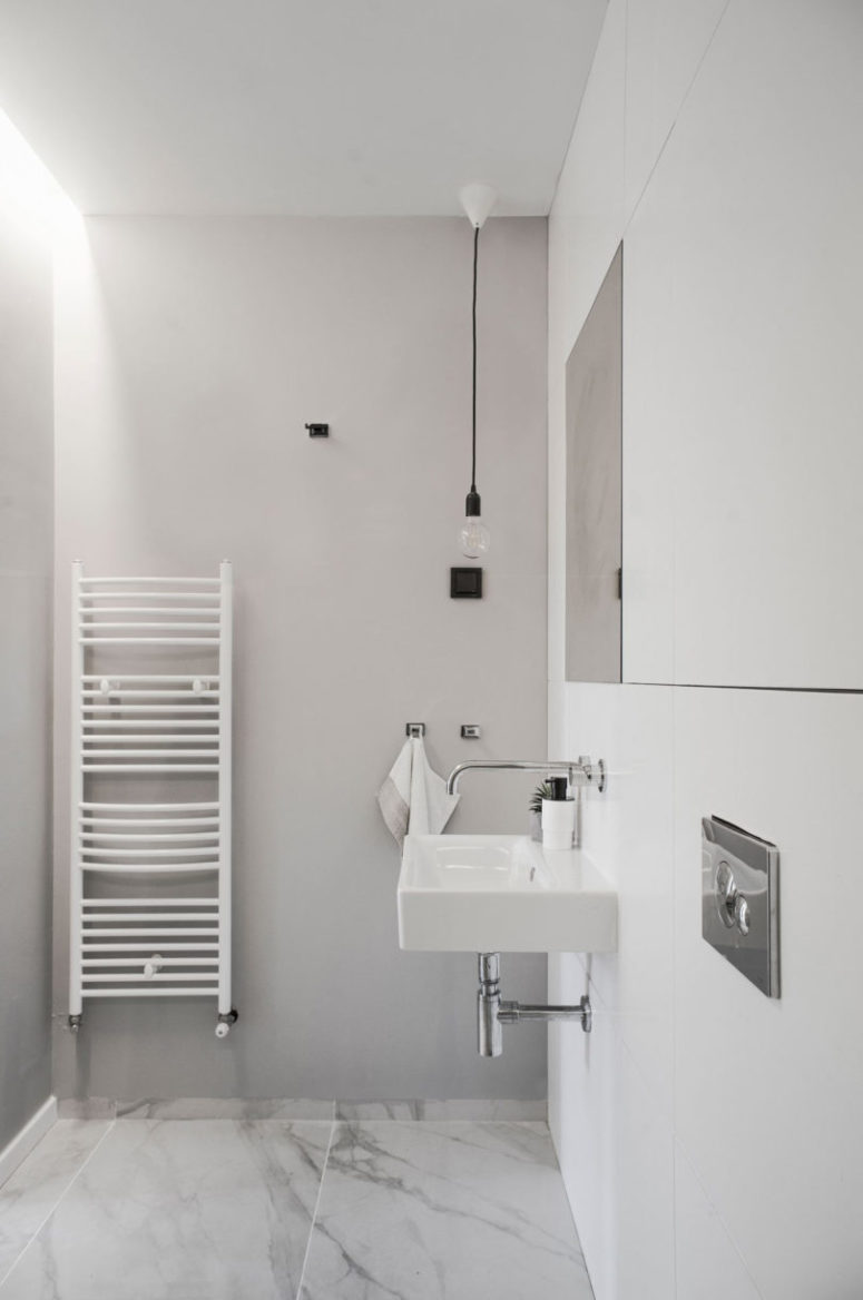 The bathroom is minimalist, with white marble tiles and bulbs plus a wall-mounted sink