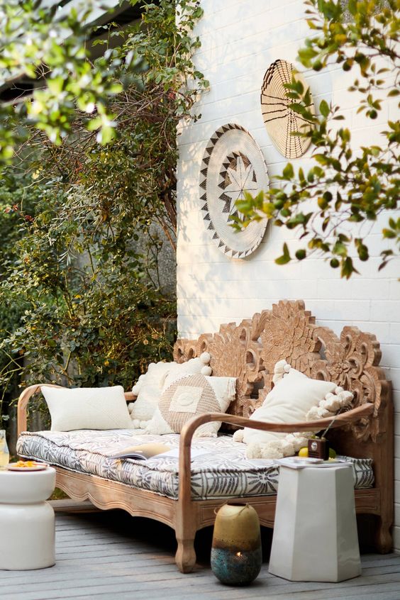 a hand carved wooden daybed with an ornate back is a gorgeous idea for a boho chic outdoor space