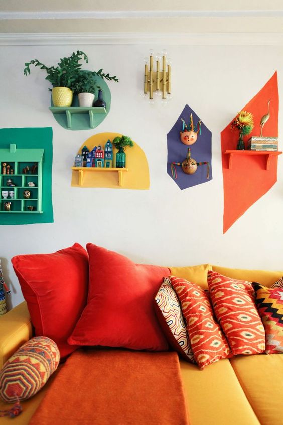 a colorful retro living room with a yellow and red sofa and bright touches on the wall - each shelf is different and highlighted with a different color