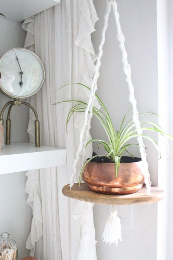 an easy hanging shelf of a cutting board and some macrame cords with a copper planter looks very boho-like