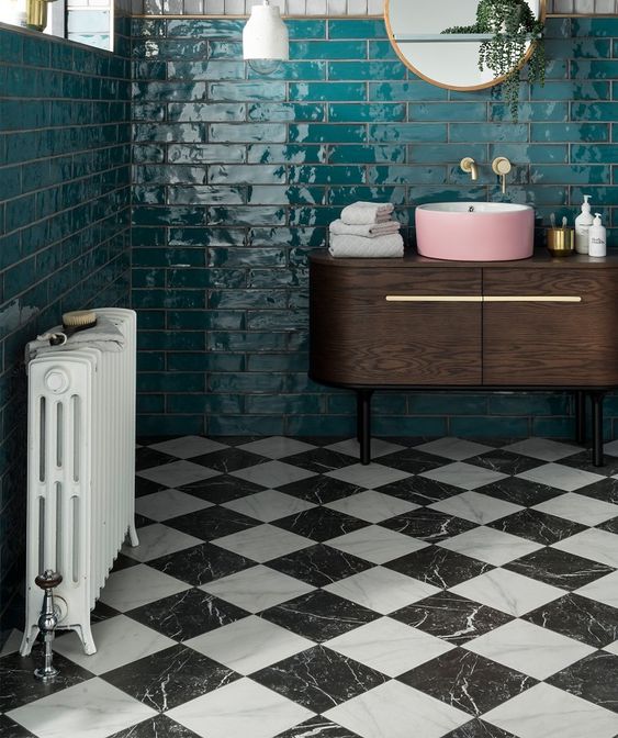 a retro bathroom with emerald tiles on the walls and black and white marble tiles on the floor