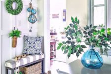 14 a bright farmhouse entryway with a greenery wreath and arrangements, a basket, floats and baskets