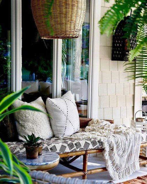 A rattan daybed with pillows, blankets and a statement wicker lampshade over it is relaxed tropical inspired idea
