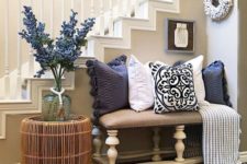 15 a bright farmhouse summer entryway with a floral arrangement, navy and white printed pillows and a rattan table
