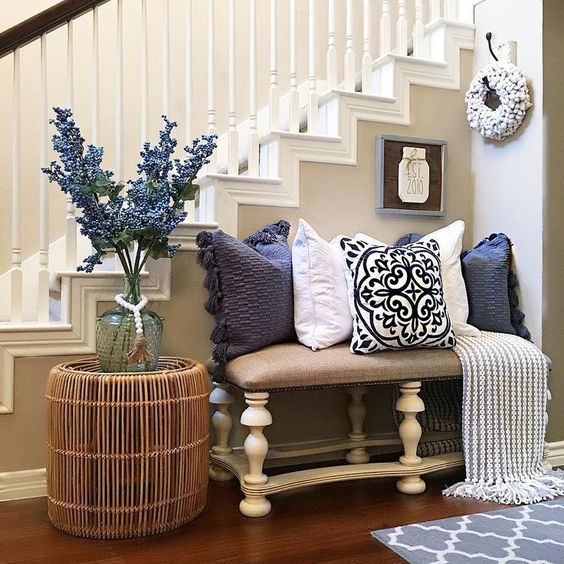 a bright farmhouse summer entryway with a floral arrangement, navy and white printed pillows and a rattan table