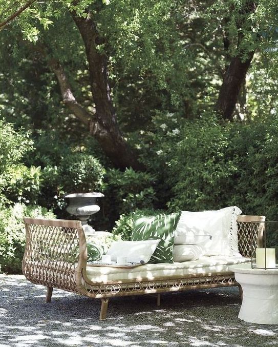 a rattan daybed with tall armrests and lots of pillows invites you to have a nap right here