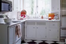 16 a 1950s inspired kitchen with a black and white tile floor and neutral cabinets yet colorful plates and pots
