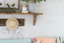 17 a bright vintage-inspired summer entryway with coral blooms in a vase and tubes, coral pillows, a straw hat and a blue bench