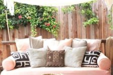 17 a recycled pallet daybed on casters with a pink cushion and an assrtoment of pillows is a veyr inviting furniture idea