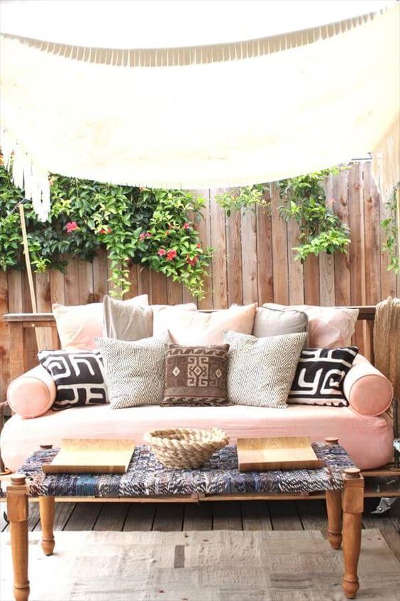 a recycled pallet daybed on casters with a pink cushion and an assrtoment of pillows is a veyr inviting furniture idea