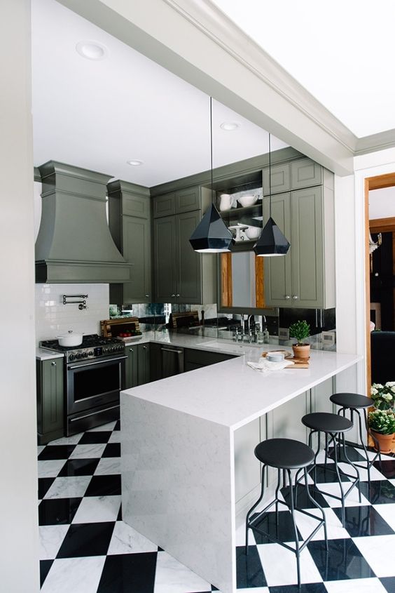 a retro kitchen renovation with green cabinets and a black and white tile floor for a more retro feel