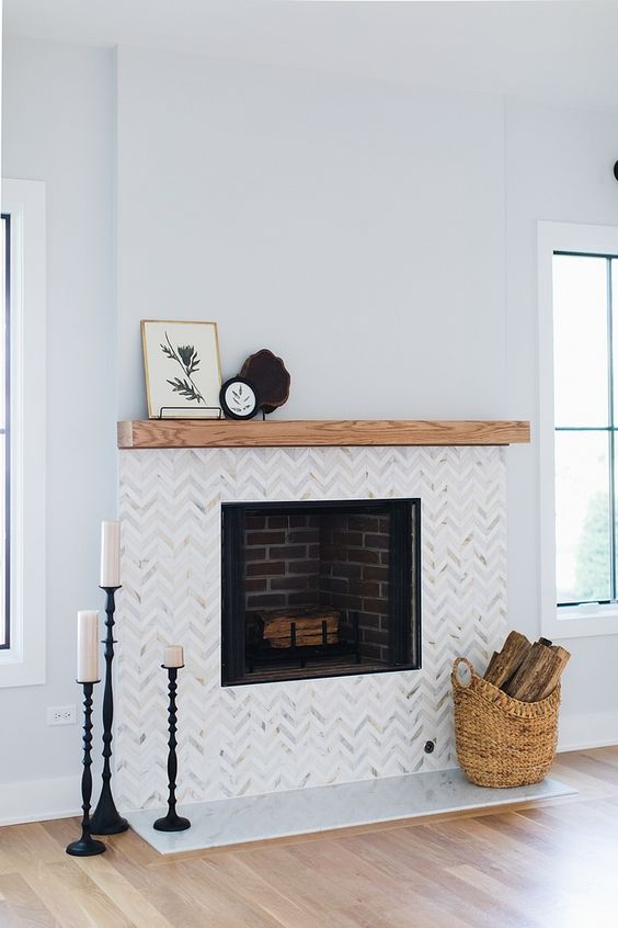 marble chevron clad tiles and a wooden mantel create a chic and stylish look and make the fireplace more elegant