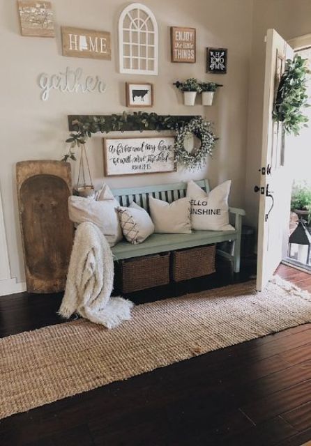 a cozy farmhouse summer entryway with a light blue bench, greenery and a greenery wreathh plus wood