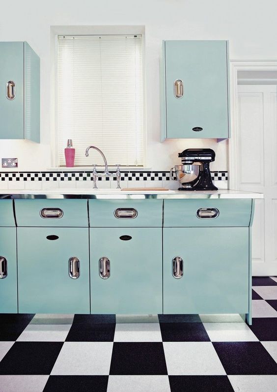 a gorgeous blue kitchen with a black and white tile floor looks really retro thanks to colors and tiles