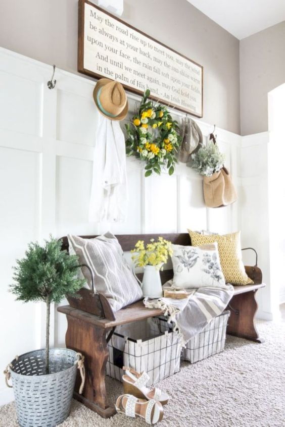 a potted plant in a bucket, a greenery and citrus wreath, yellow blooms and botanical print pillows for summer vibes