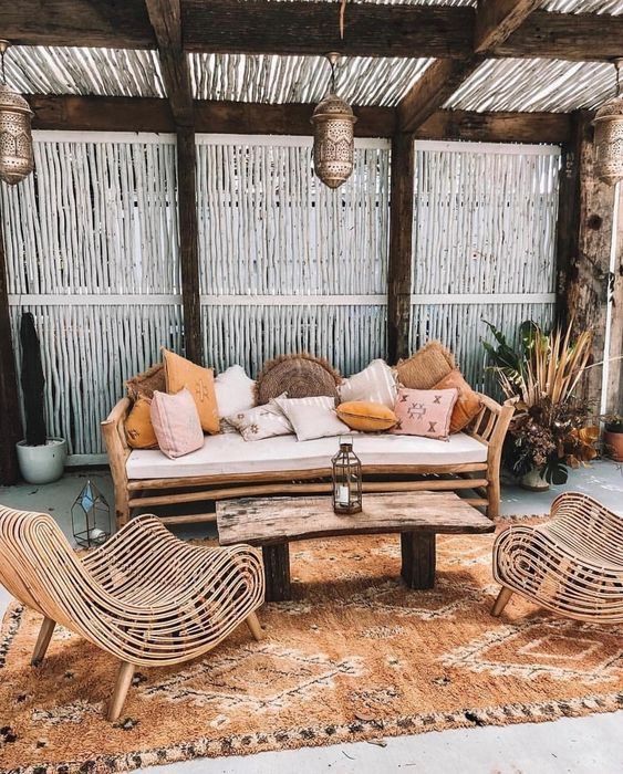 a simple rattan daybed with lots of muted color pillows is the main piece in this boho terrace