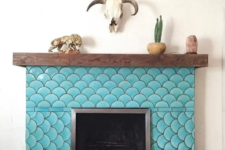 21 a rustic fireplace with a wooden mantel is spruced up with turquoise fish scale tiles to create an optical illusion and make a statement with color