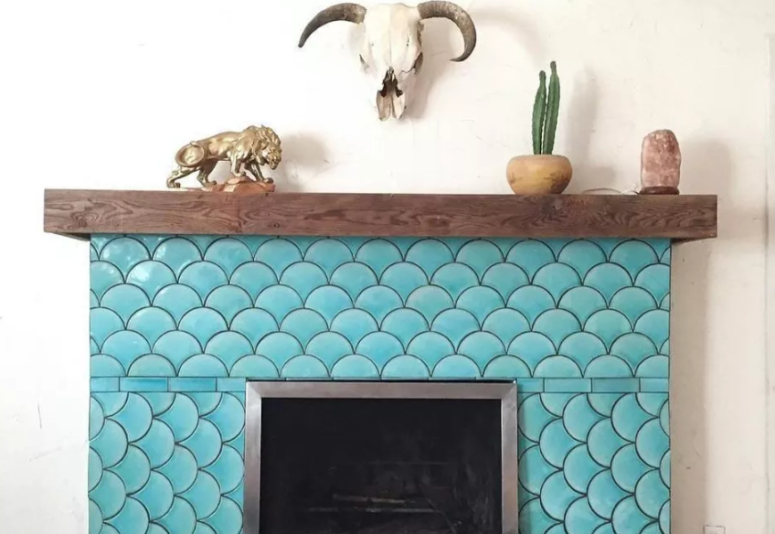 a rustic fireplace with a wooden mantel is spruced up with turquoise fish scale tiles to create an optical illusion and make a statement with color