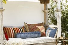 22 a whitewashed wooden daybed with a roof over it and lot sof colorful pillows is a gorgeous boho place to have a siesta