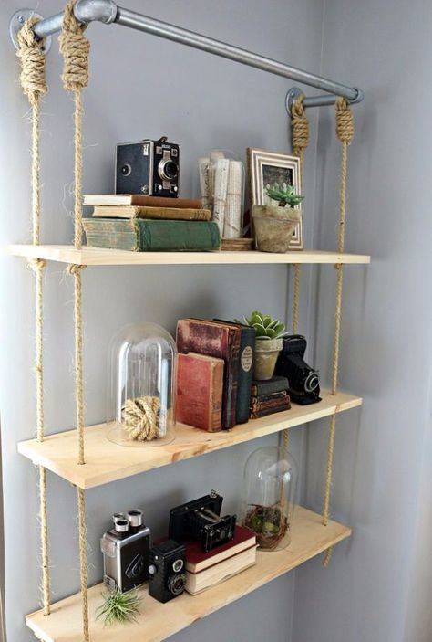 an industrial pipe with a hanging shelving unit with thin plywood tiers and ropes is a cool idea for an industrial space