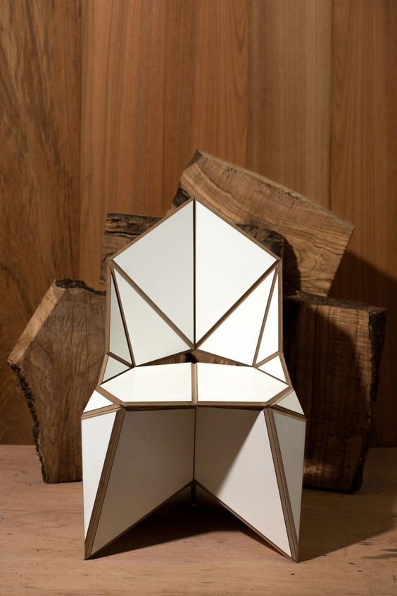 a white geometric and sculptural chair with gold touches looks very futuristic and super bold