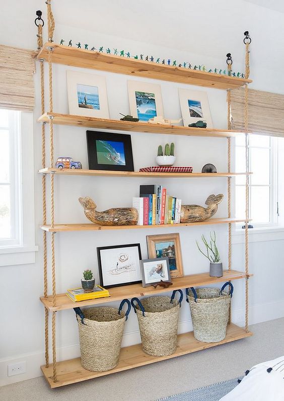 an oversized hanging shelving unit with ropes and shelves going down to the floor and baskets on the lowest piece
